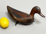 a wooden duck sitting next to a lemon on a table