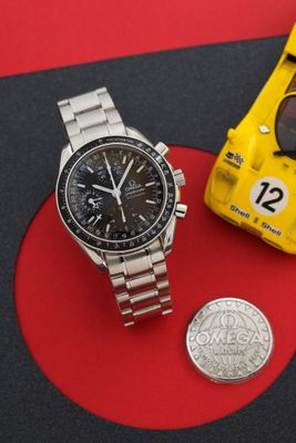 une montre et une petite voiture posées sur un fond rouge