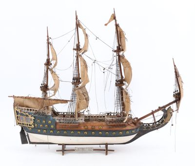 maquette en bois d'un grand voilier posée sur une surface blanche