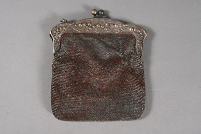 un vieux sac à main en argent avec une anse ornée de perles sur un fond blanc