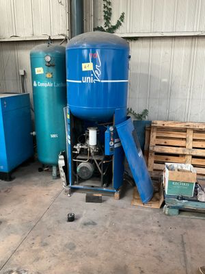 a large blue tank sitting in a garage next to other blue tanks