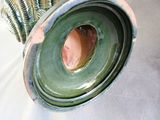 a green vase with a hole in it sitting on a table