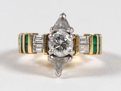 une photo d'une bague sertie d'un diamant et d'une émeraude sur un fond blanc