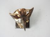 a metal object with a flower on it on a white surface