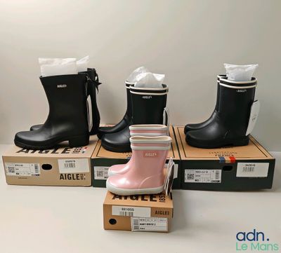 three pairs of pink and black rain boots sitting on top of boxes