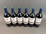 six bottles of wine lined up in a row on a table