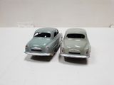 two toy cars sitting side by side on a white surface
