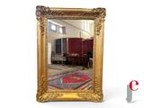 a gold framed mirror with a red rug on the floor