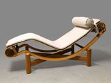 a white chaise lounger with a roll of fabric on top of it