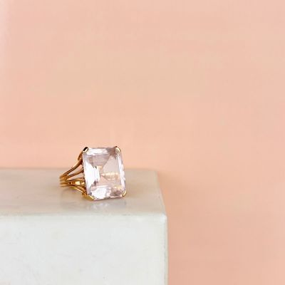un gros plan d'une bague posée sur un socle, sur fond rose