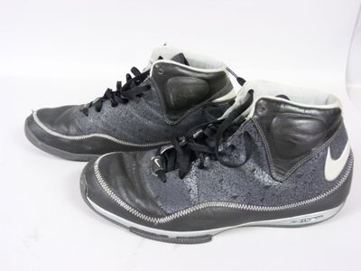une paire de baskets noires et blanches posées sur une surface blanche, sur fond blanc