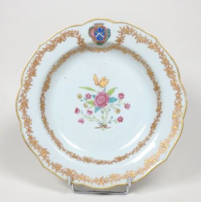 une assiette blanche bordée d'or et décorée de fleurs