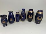 five blue vases with gold designs are lined up against a white background