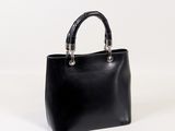 a black leather handbag with a metal handle on a white background