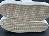 the soles of a pair of white sneakers on a black surface