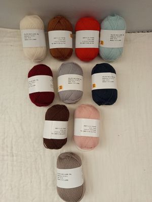 de nombreuses pelotes de laine posées sur une serviette, par terre