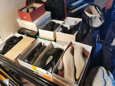 de nombreuses paires de chaussures dans des cartons posés sur un piano
