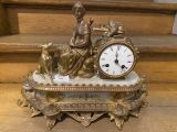 a clock sitting on top of a table with a statue on top of it