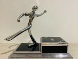 statue of a man holding a tennis racquet on top of a wooden table