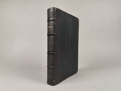un vieux livre noir posé sur une table blanche