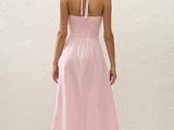 a woman in a pink dress standing in front of a white wall