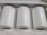 three white wifi routers in a box on a wooden table