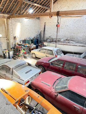 many old cars in a garage that is being worked on