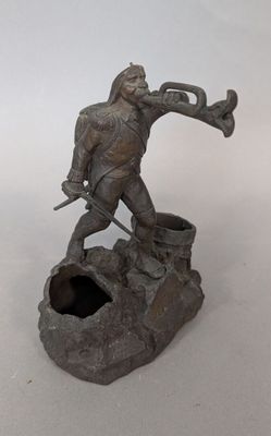 statue of a man with a trumpet on a rock with a hole in the ground