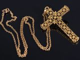 a close up of a cross on a chain on a black surface