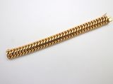 gros plan d'un bracelet en or sur une surface blanche