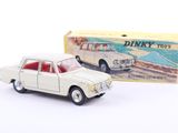 une petite voiture miniature devant une boîte de Dinky Toys