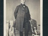 portrait d'un homme vêtu d'un long manteau, debout à côté d'une chaise