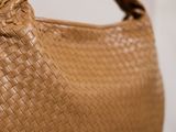 woven leather handbag on a table with a white wall in the background