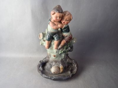 a figurine of a boy and a girl sitting on a tree branch
