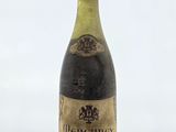 une vieille bouteille de vin posée sur une table blanche