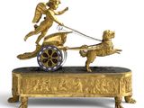 une figurine en or représentant un ange tirant une charrette avec un chien