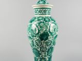 a green and white vase sitting on top of a table