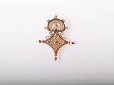 un pendentif en or orné d'une horloge, posé sur une surface blanche