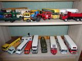 de nombreux camions et bus miniatures posés sur une étagère dans une pièce
