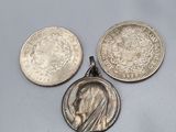 trois pièces d'argent et un pendentif en argent sur un fond gris