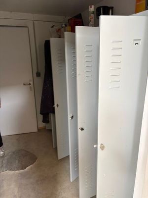 Plusieurs casiers sont alignés dans une pièce, et une personne se tient dans l'embrasure de la porte.