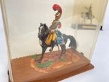 a figurine of a man riding a horse in a glass case