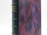an old book with a purple cover sitting on a white surface