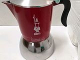 a red coffee pot sitting on a counter next to a plastic container