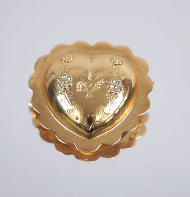 a gold heart shaped brooch with diamonds on it