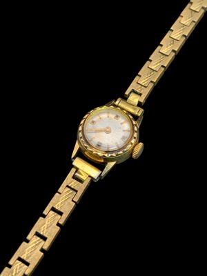une image montrant un gros plan d'une montre en or sur fond noir