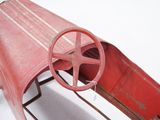 a red toy airplane with a steering wheel on a stand