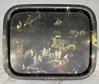 un plateau noir orné d'une peinture, posé sur une table
