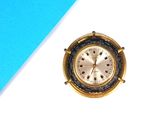 une petite horloge dorée posée sur une table bleue et blanche