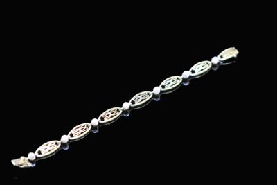 a close up of a silver bracelet on a black background